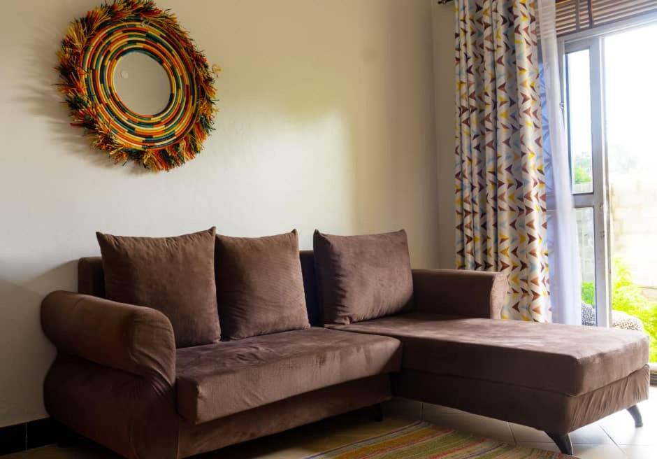 ein braunes Sofa im Wohnzimmer mit Spiegel in der Unterkunft FARANT Homes in Kampala
