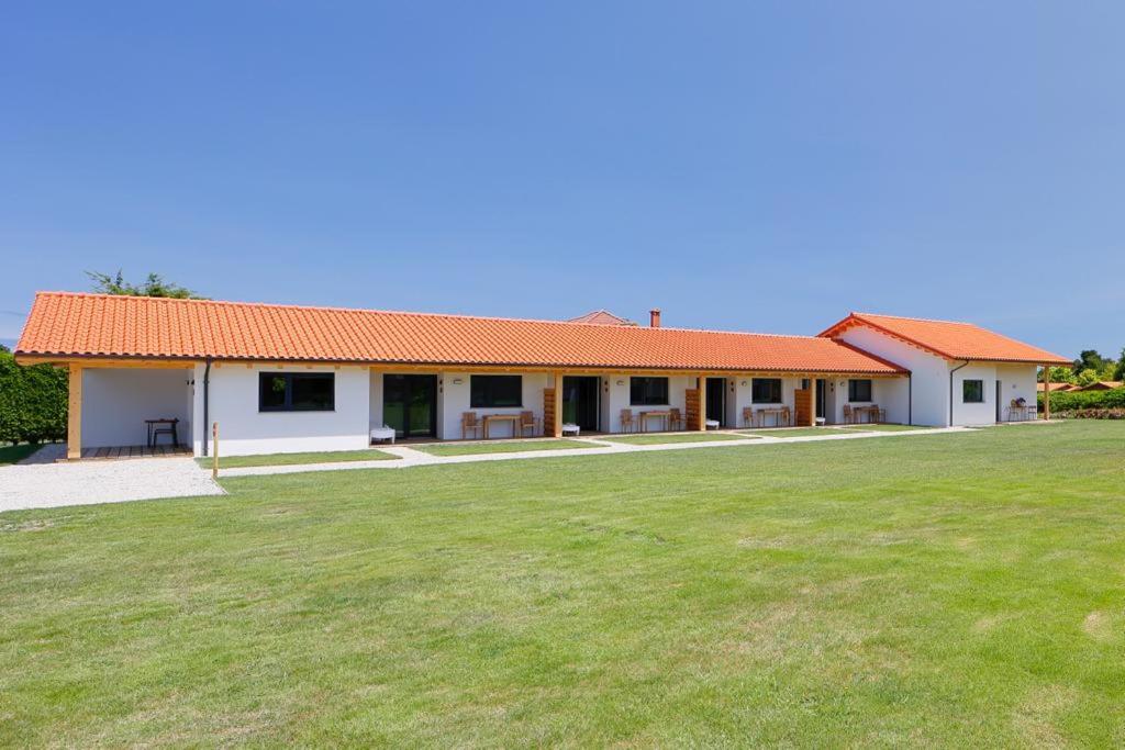 a white building with an orange roof and a grass field at Apartamentos Aronces in Cudillero