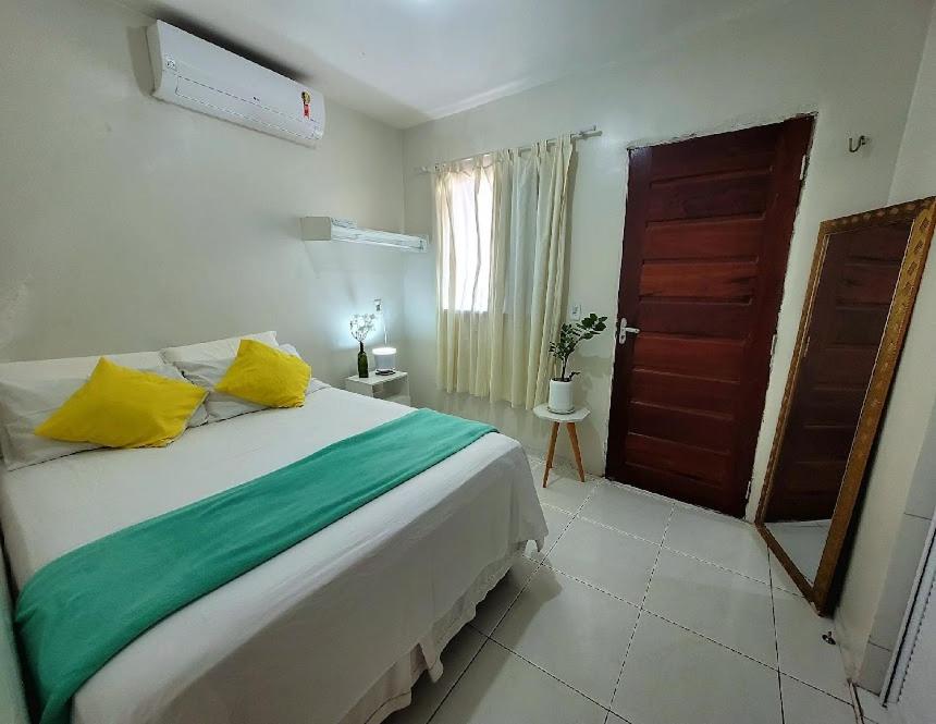 um quarto com uma cama grande com almofadas amarelas e verdes em Teto Hospedagens em Fortaleza