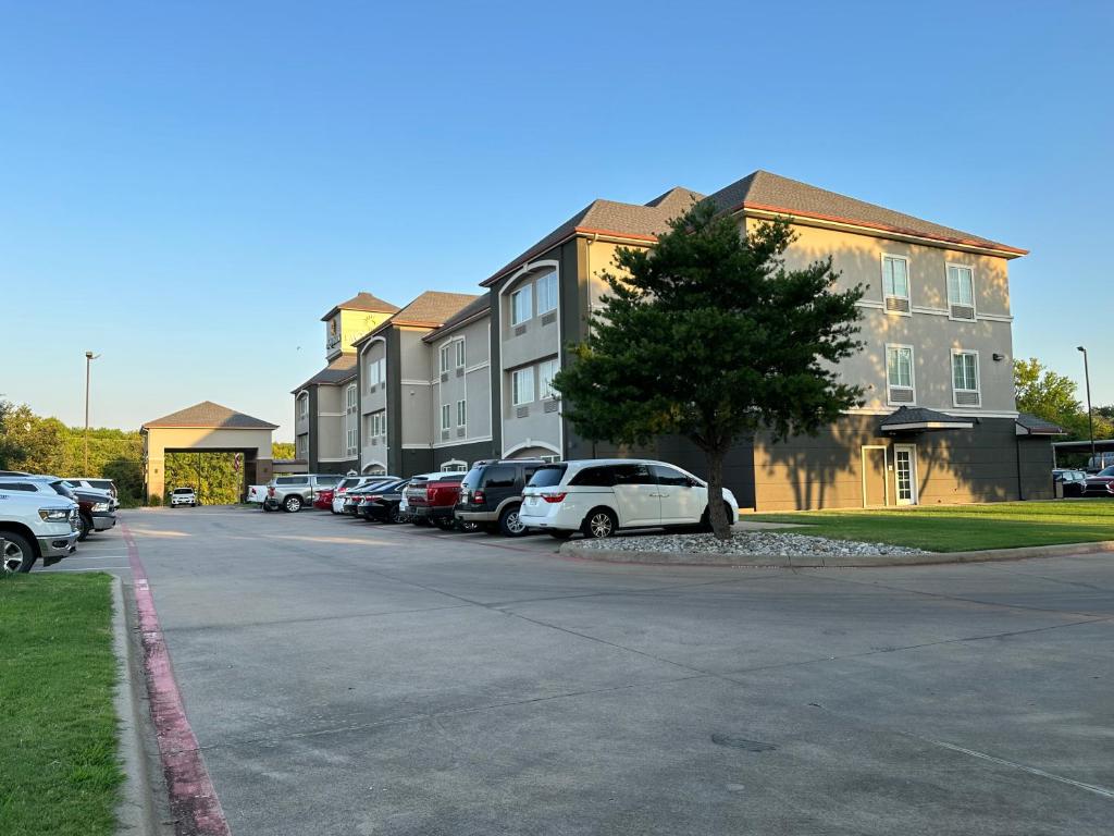 a parking lot with cars parked in front of buildings at La Quinta by Wyndham Sulphur Springs in Sulphur Springs