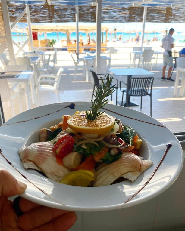a person holding a plate of food on a cruise ship at Blue Paradise Hotel in Orikum