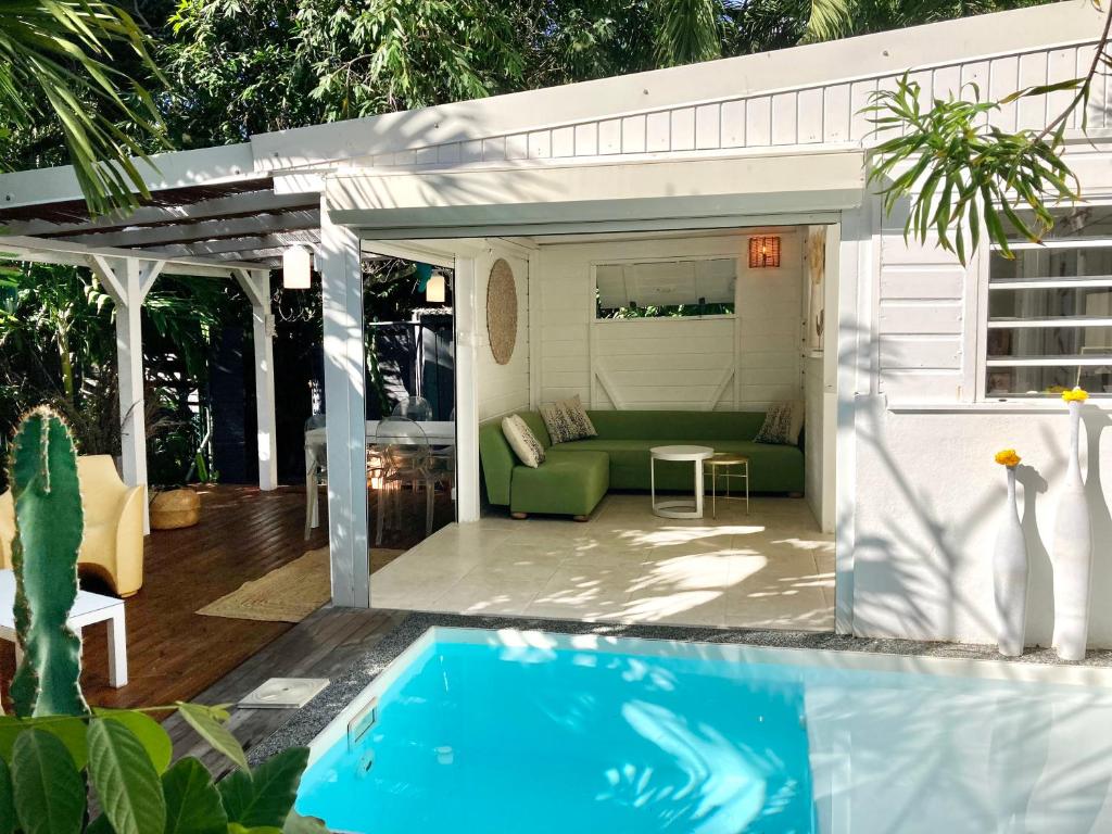 un patio trasero con piscina y una casa en 17 Les Palmes - Maison de charme - Piscine privée et accès plage, en Sainte-Anne