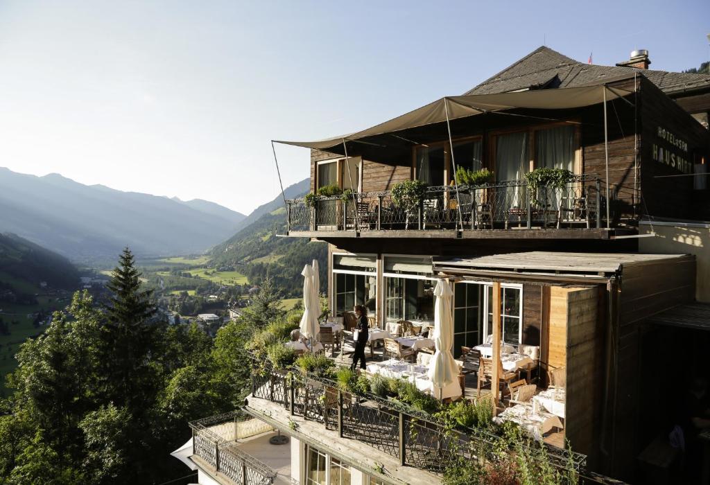 un edificio con balcón con mesas y sillas en Alpine Spa Hotel Haus Hirt, en Bad Gastein