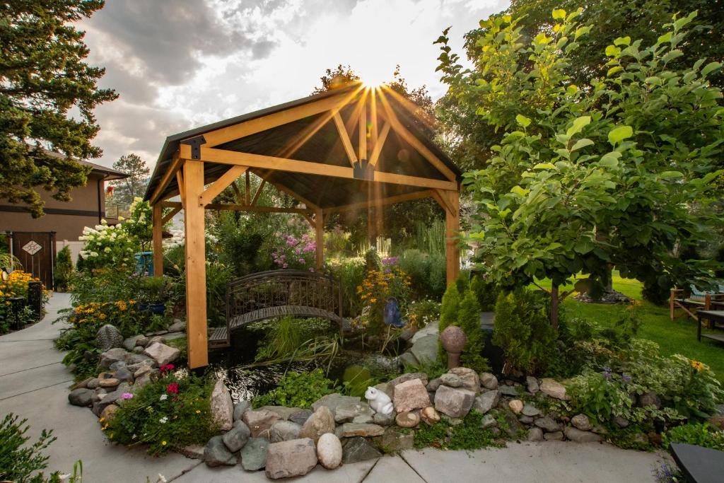 a wooden gazebo in a garden with flowers at Rayleigh Riverfront Retreat- Peaceful Garden Oasis-25 MINUTES TO SKI HILL in Kamloops