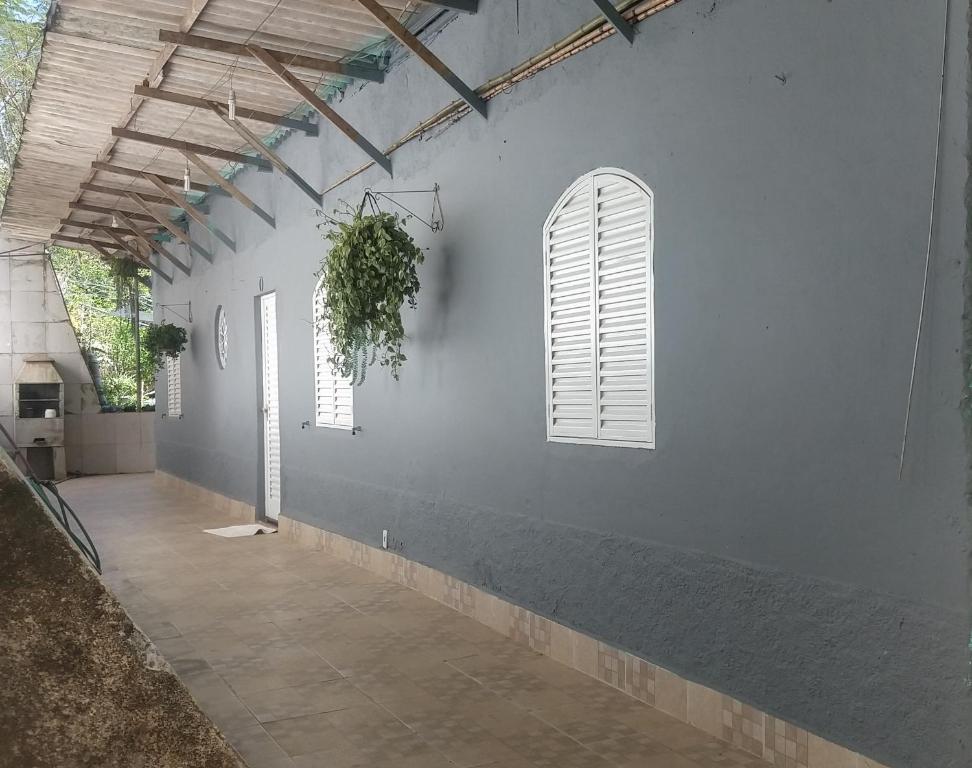 a white wall with two windows and a plant at Casa do Mirante in Petrópolis