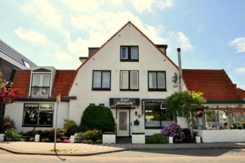 a white house with black windows on a street at Hotel Brinkzicht in De Koog