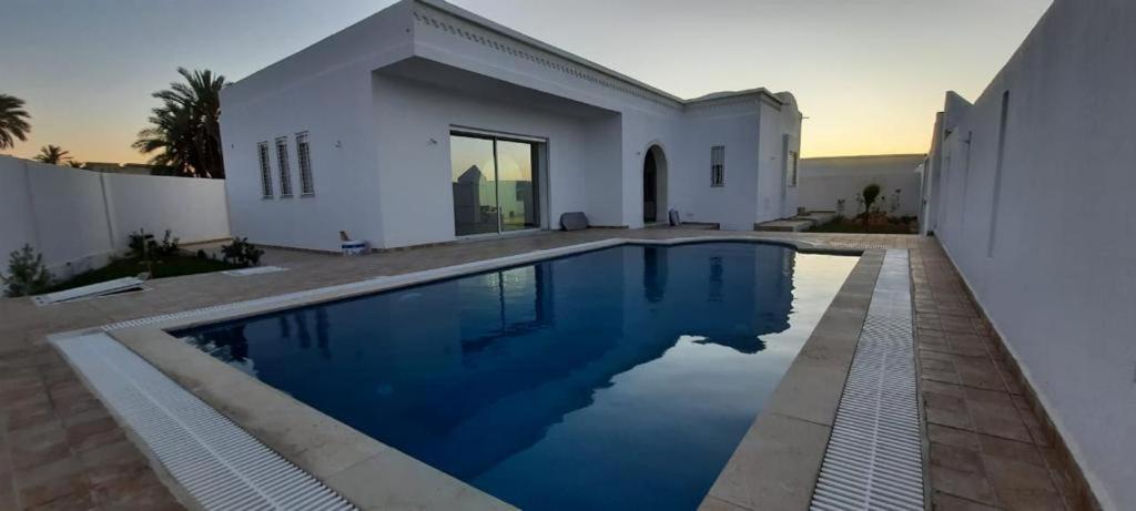 a swimming pool in front of a white house at Villa Lucia in Djerba