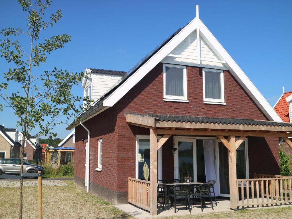 a red brick house with a porch and a table at Lakeview villa with swimming and fishing pier in Simonshaven