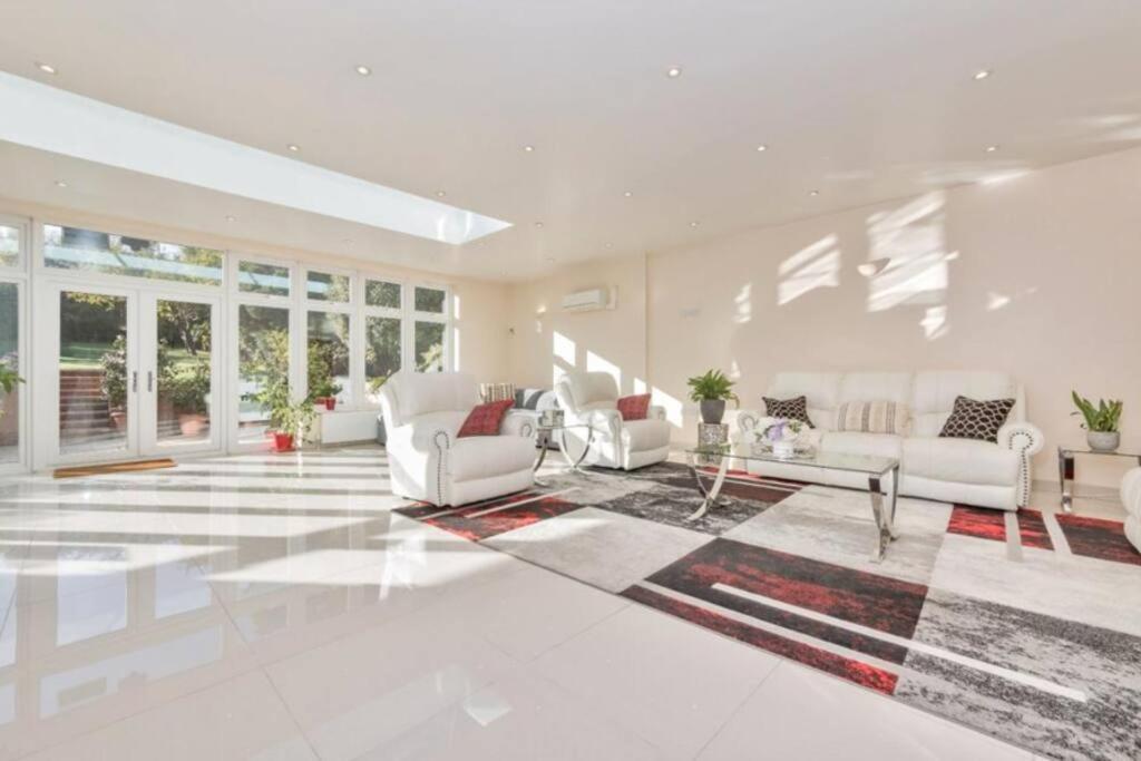 a large living room with white furniture and windows at Rose Garden House in Luton
