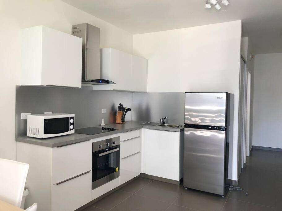 a kitchen with white cabinets and a stainless steel refrigerator at Convenient Studio Apt Near Airport, Beaches & Food in Cupecoy
