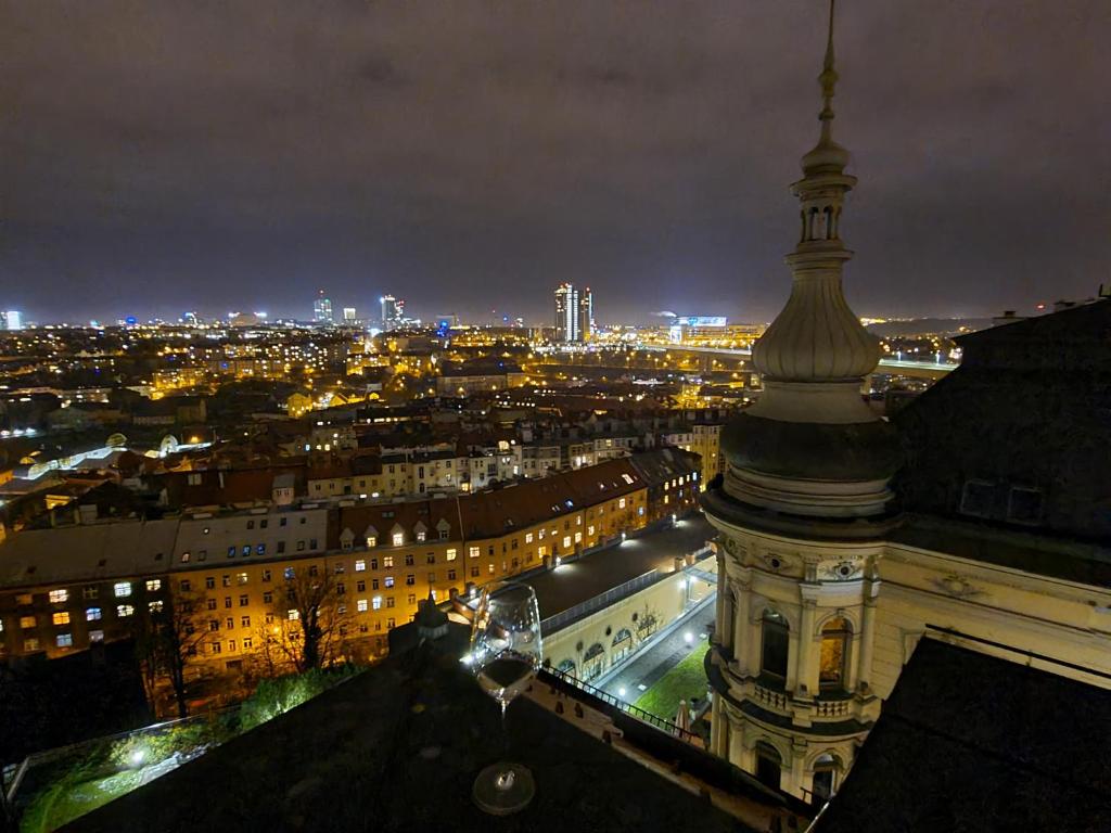 Blick auf die Stadt in der Nacht mit einem Glas Wein in der Unterkunft Luxury rooftop appartment with fantastic views in Prag
