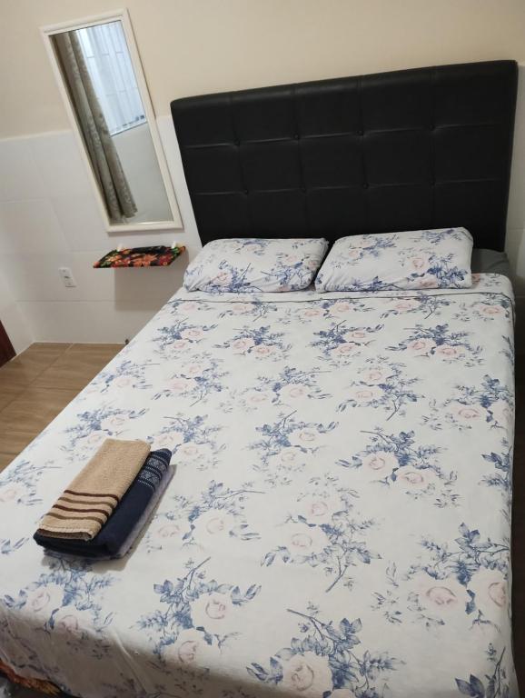 a bed with a blue and white comforter with a black headboard at FLORIPA FLORINDO APART in Florianópolis