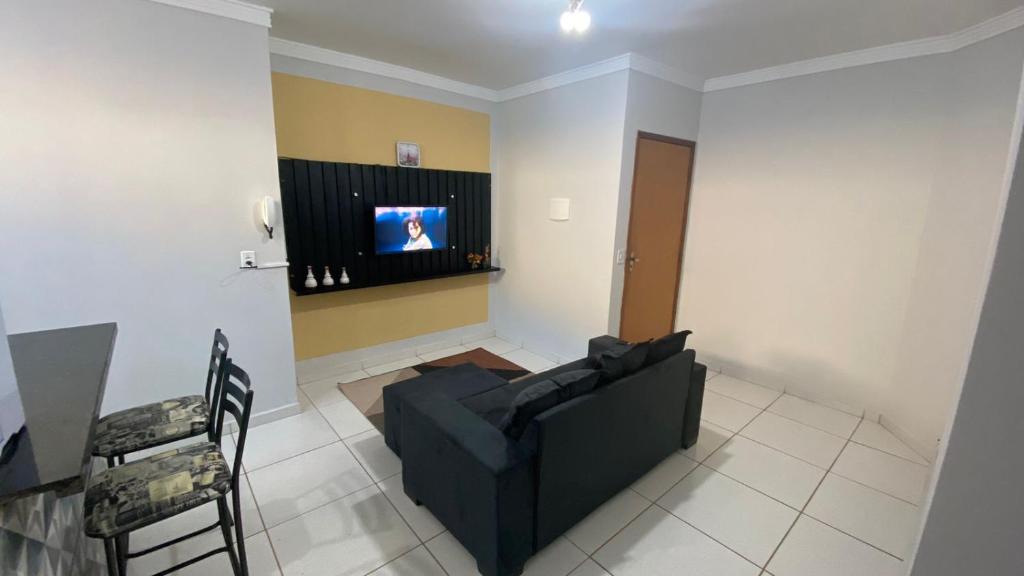 uma sala de estar com um sofá preto e uma televisão em Apartamento Daia Prox Caoa em Anápolis