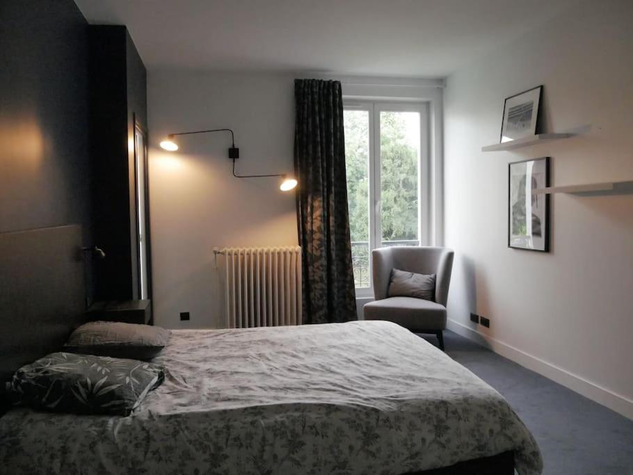 a bedroom with a bed and a chair and a window at Villa piscine city center / 15 min Chps Elysées in Nanterre