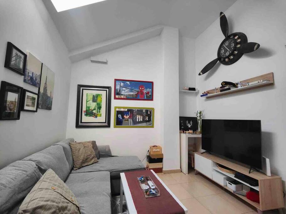 ein Wohnzimmer mit einem Sofa und einem Flachbild-TV in der Unterkunft Apartamento recién reformado en Barajas Pueblo in Madrid