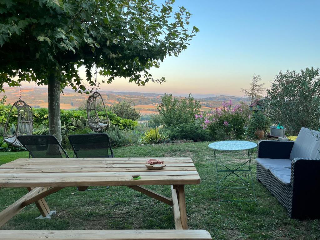 een houten picknicktafel en stoelen in een tuin bij Figuets 3 in Châteauneuf-de-Galaure
