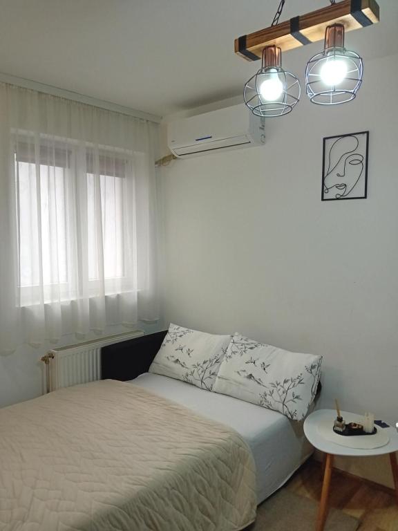 um quarto branco com uma cama e uma mesa em Apartman,, Nina ,, em Jagodina