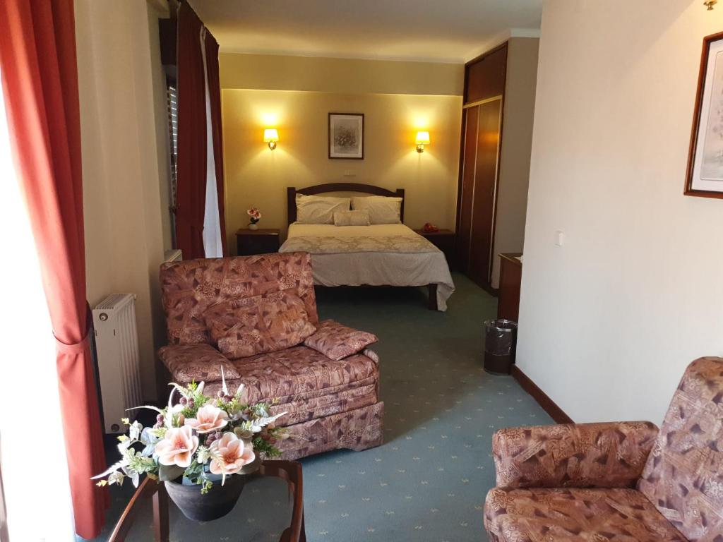 una camera d'albergo con letto, divano e sedie di Hotel Peninsular a Monte Real