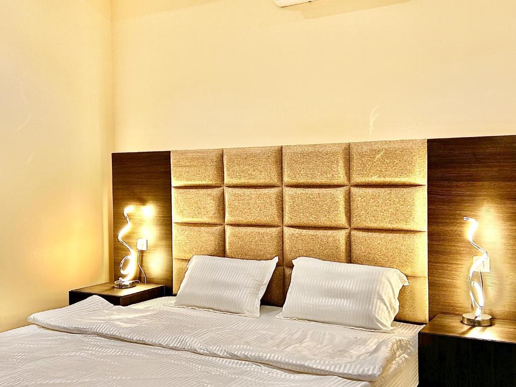 a bedroom with a large bed with two lamps at شقة خاصة مؤثثة بالكامل للتأجير اليومي in Hafr Al Baten