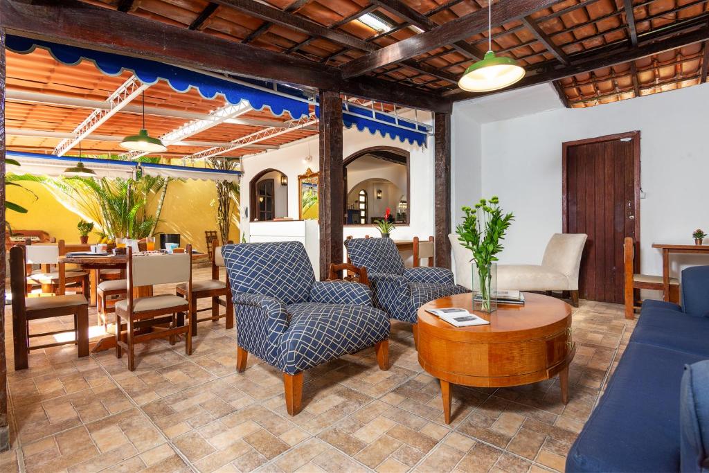 a living room with blue chairs and a table at Pousada Via Mar Búzios in Búzios