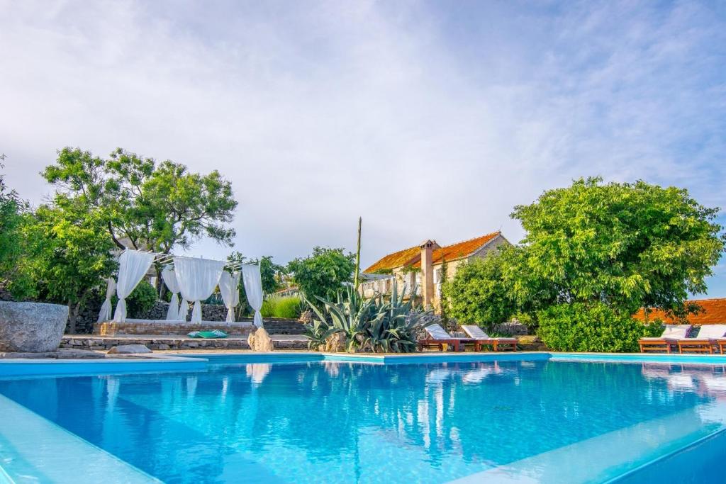 une grande piscine d'eau bleue en face d'une maison dans l'établissement Sea View Villa Dvori Sv. Jurja, à Jelsa