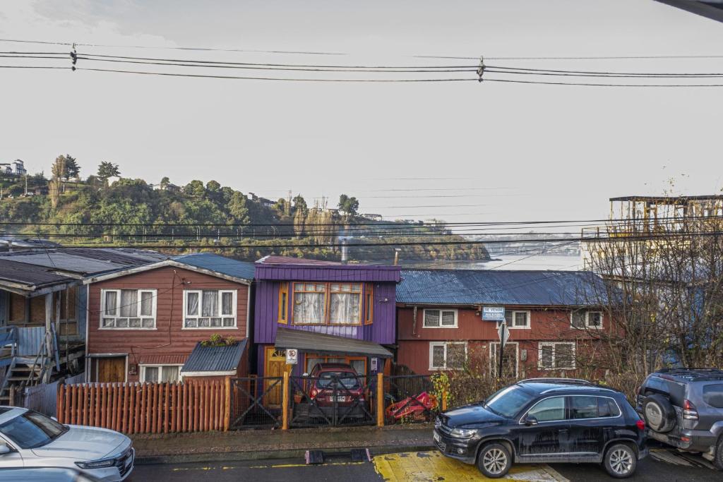 a group of houses with cars parked in a parking lot at Refugio Ballena Hostel in Castro