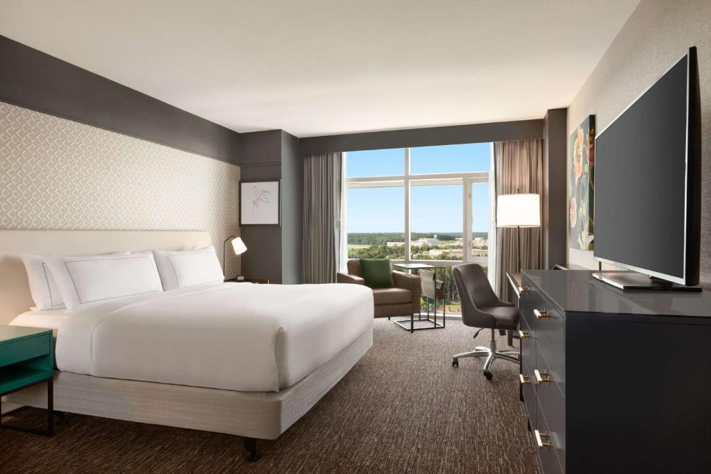 a hotel room with a bed and a desk with a television at Hilton Baltimore BWI Airport in Linthicum Heights