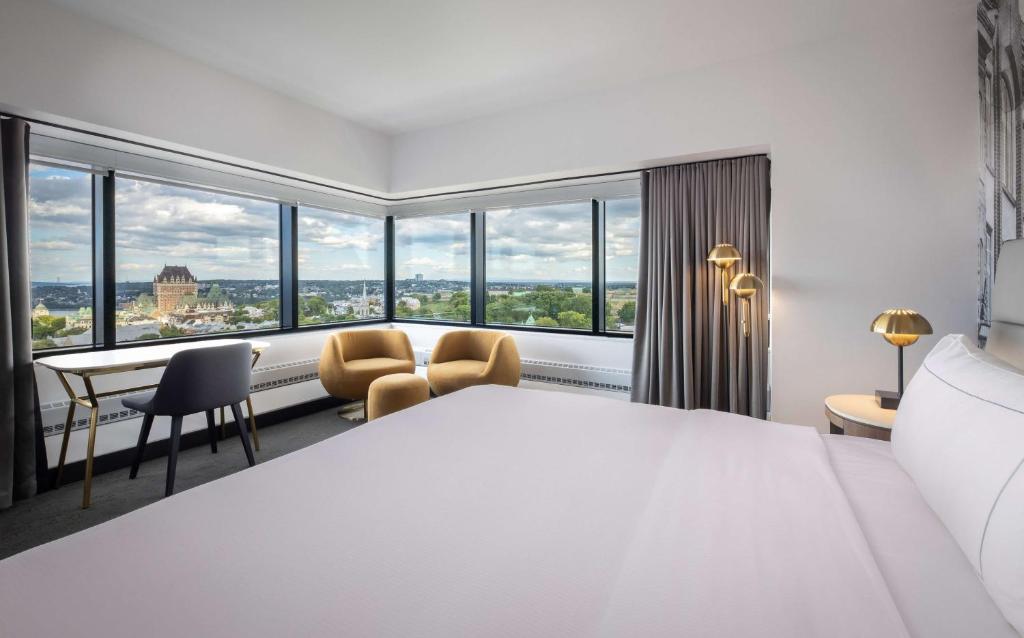 Habitación de hotel con cama grande y ventanas grandes. en Hilton Québec, en Quebec