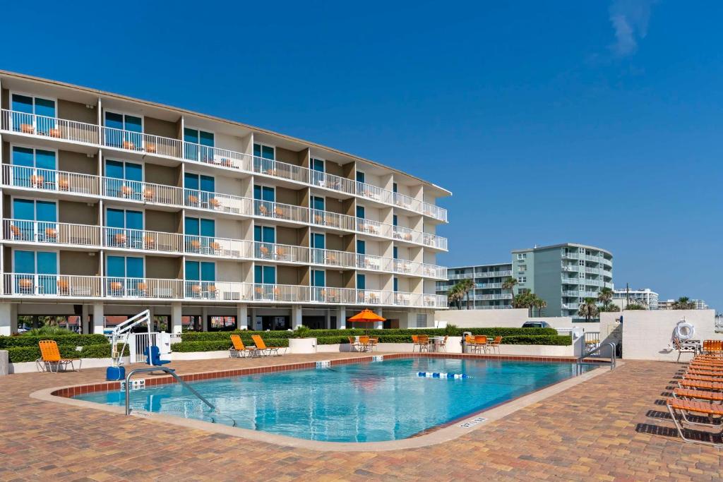 a hotel with a swimming pool in front of a building at Best Western Plus Daytona Inn Seabreeze in Daytona Beach