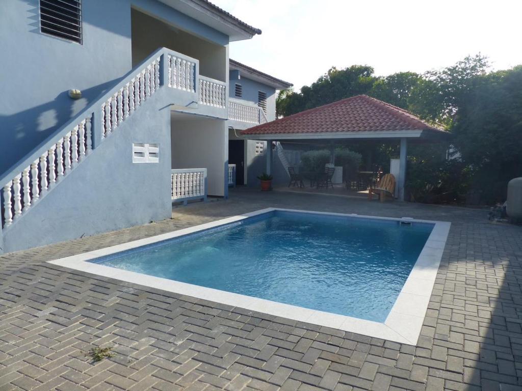 a swimming pool in front of a house at Cattleya Apartments Curacao in Willemstad