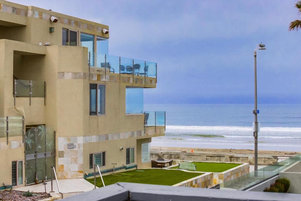 a building with a balcony overlooking the beach at OceanCatcher - newly remodeled 3 bedroom retreat with ocean view in the heart of Mission Beach, sleeps 10 in San Diego