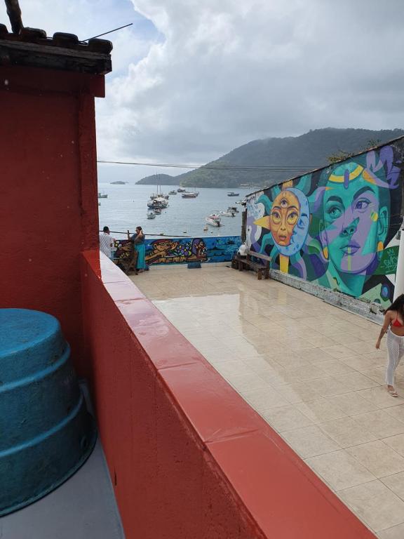 a wall with a mural of faces on it next to the water at Casa do Cais in Abraão