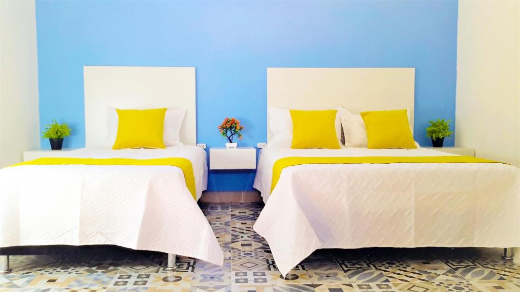 two beds with yellow pillows in a blue room at Believer Hostel in Santa Marta