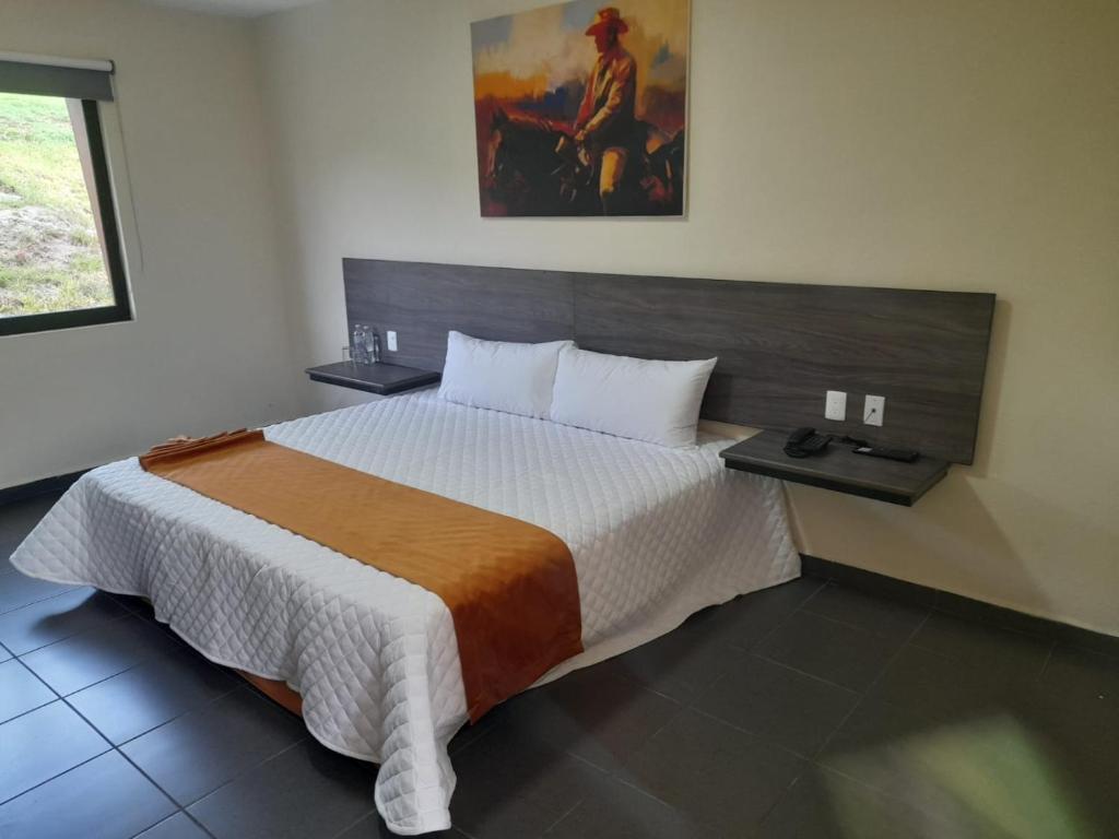 a bedroom with a bed and a painting on the wall at LOS BAMBUES HOTEL in La Tinaja