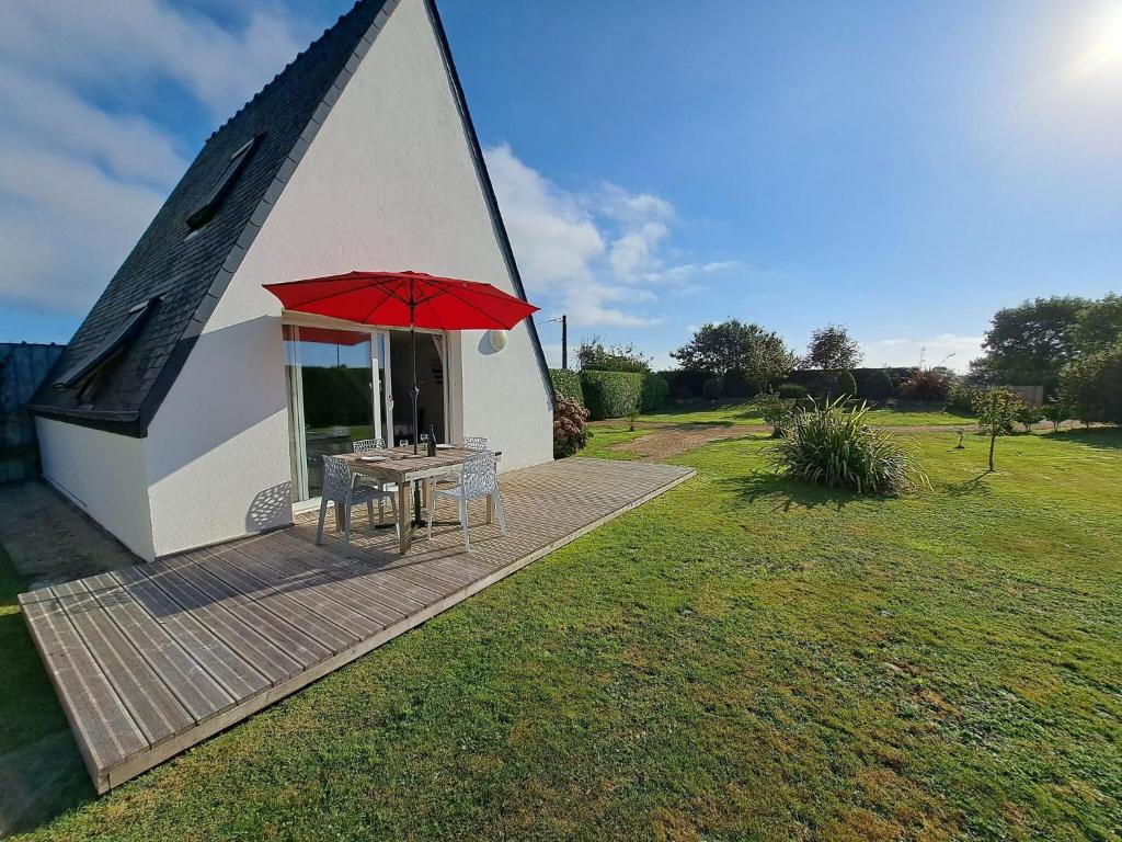 einen Tisch mit einem roten Regenschirm auf dem Deck in der Unterkunft Cottage, Beuzec Cap Sizun in Beuzec-Cap-Sizun