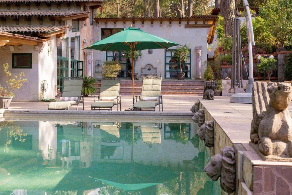 a house with a swimming pool with a green umbrella at ¡Increíble casa en Avándaro para 10 personas! in Valle de Bravo