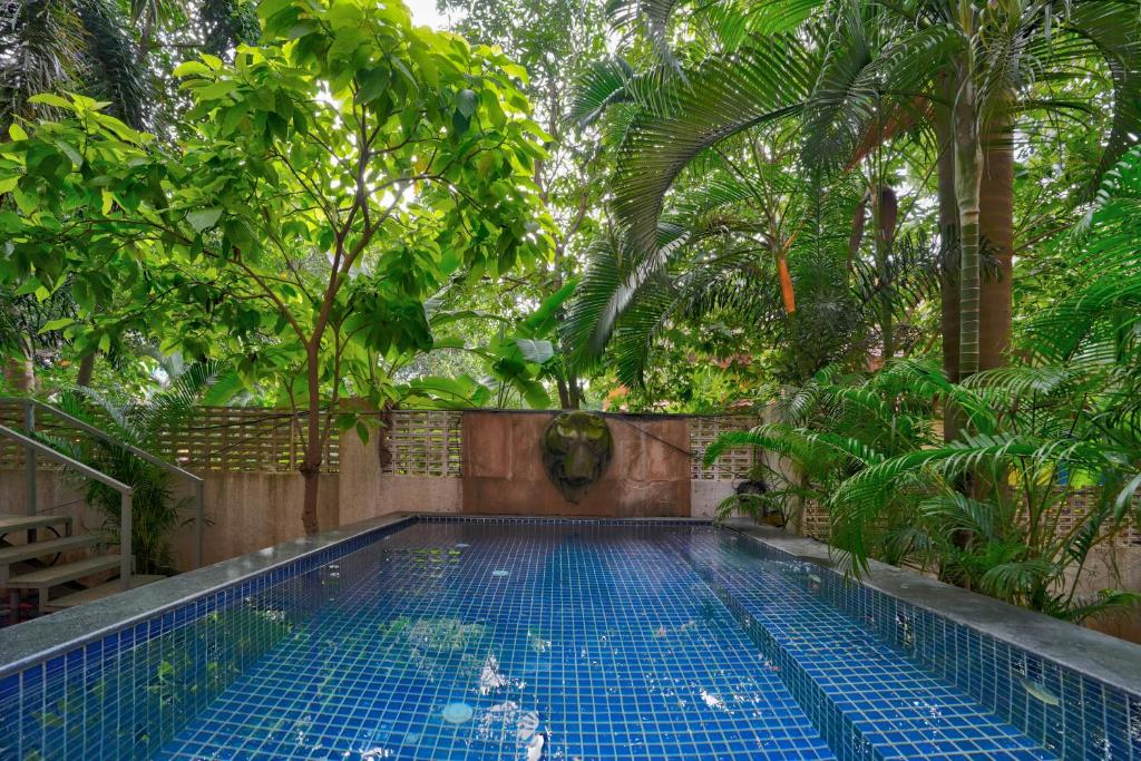 a swimming pool in a garden with trees at Luxury 4BHK Villa with Private Pool Near Candolim in Marmagao