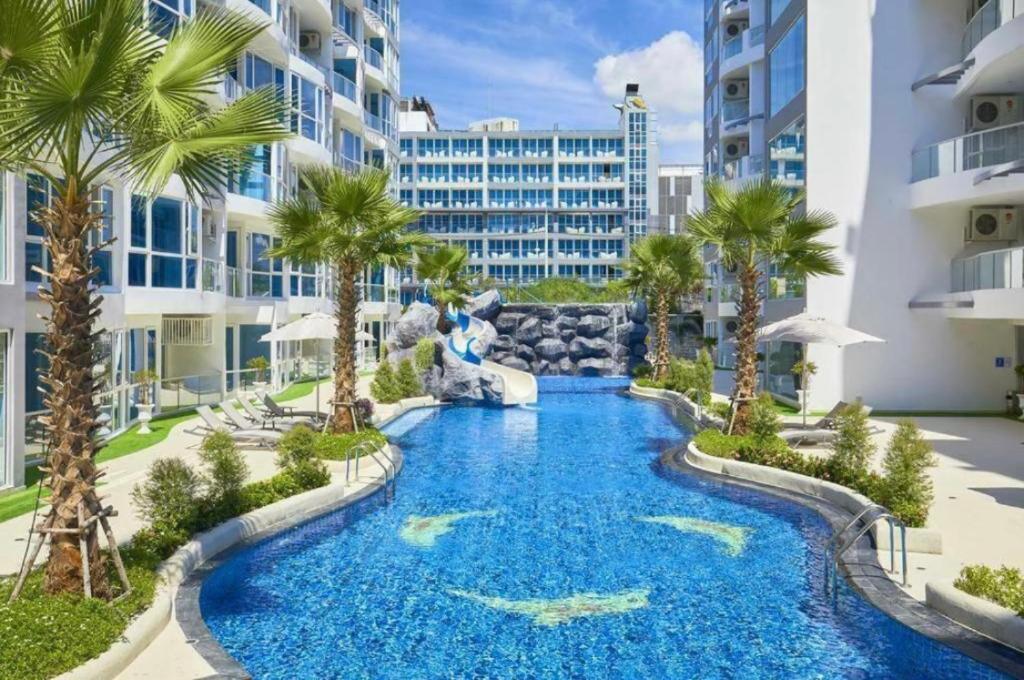 a pool in the middle of a resort with palm trees at Large Deluxe Condo Grand Avenue Central Pattaya in Pattaya Central