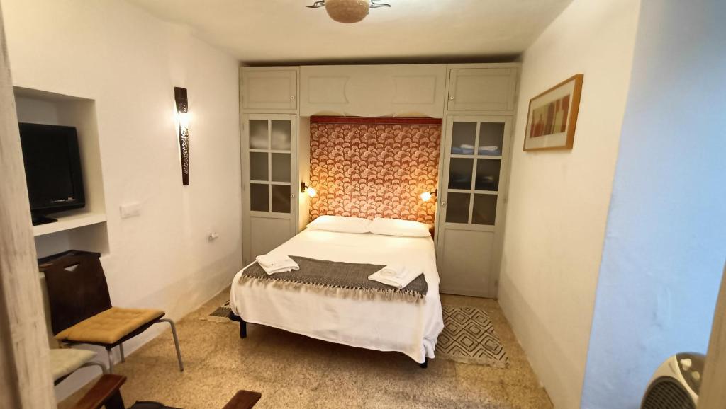 a small bedroom with a bed and a chair at Casa James in Vejer de la Frontera