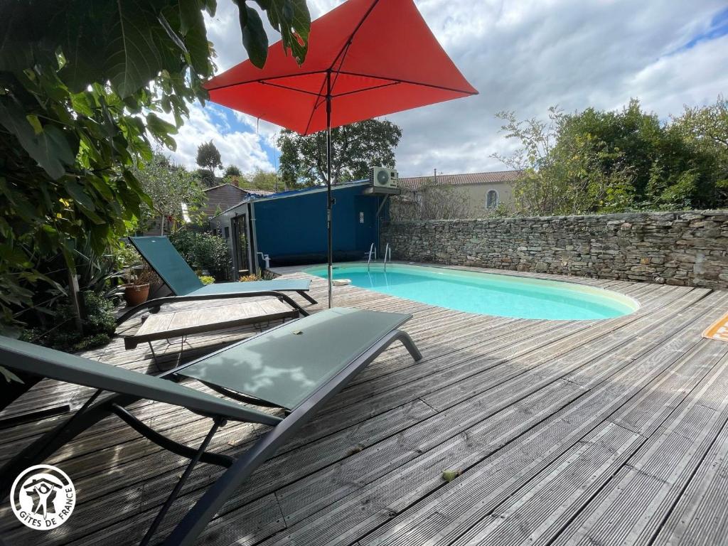 una terraza con 2 sillas y una sombrilla junto a la piscina en Gîte Mareuil-sur-Lay-Dissais, 3 pièces, 5 personnes - FR-1-426-537, en Mareuil-sur-Lay