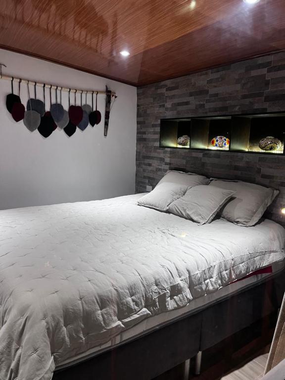 1 dormitorio con 1 cama grande y pared de ladrillo en Cabaña Los Cedros, en La Vega