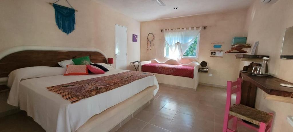 a bedroom with a bed and a desk and a window at Casa Tzalam Tulum selva in Tulum