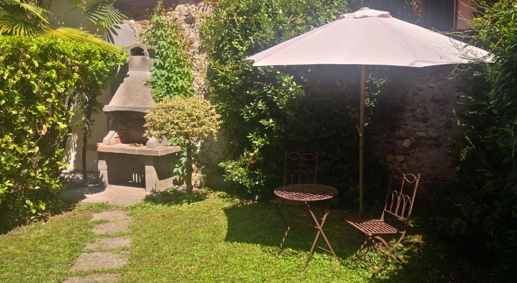 - un jardin avec un parasol, une table et des chaises dans l'établissement Residenza Esse, à Angera