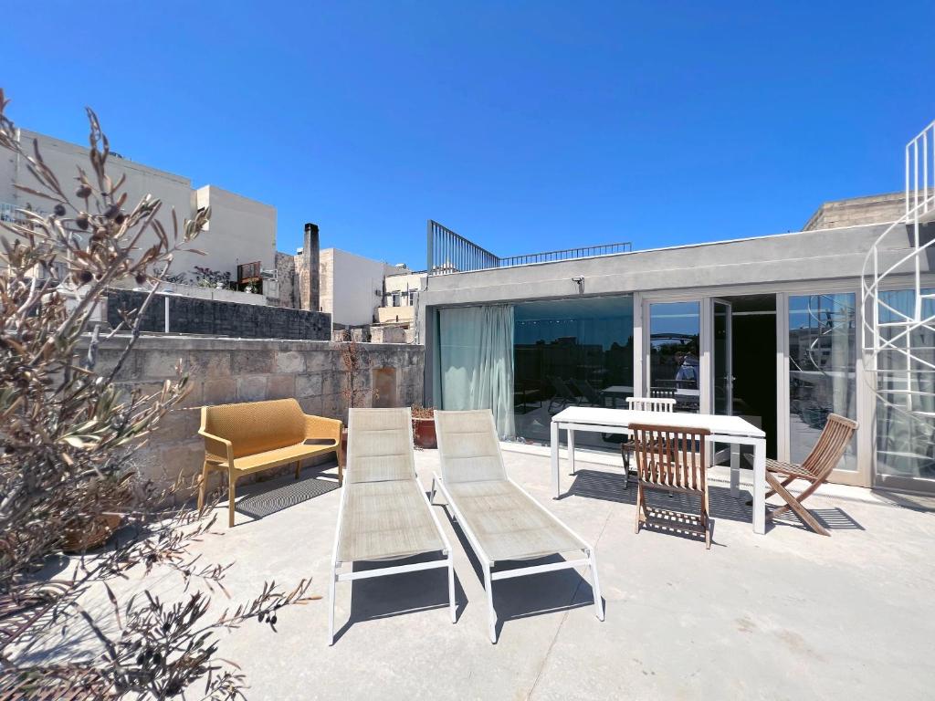 Un patio con sillas y una mesa en un edificio. en CASA NOBILE APARTMENTS, en La Valeta