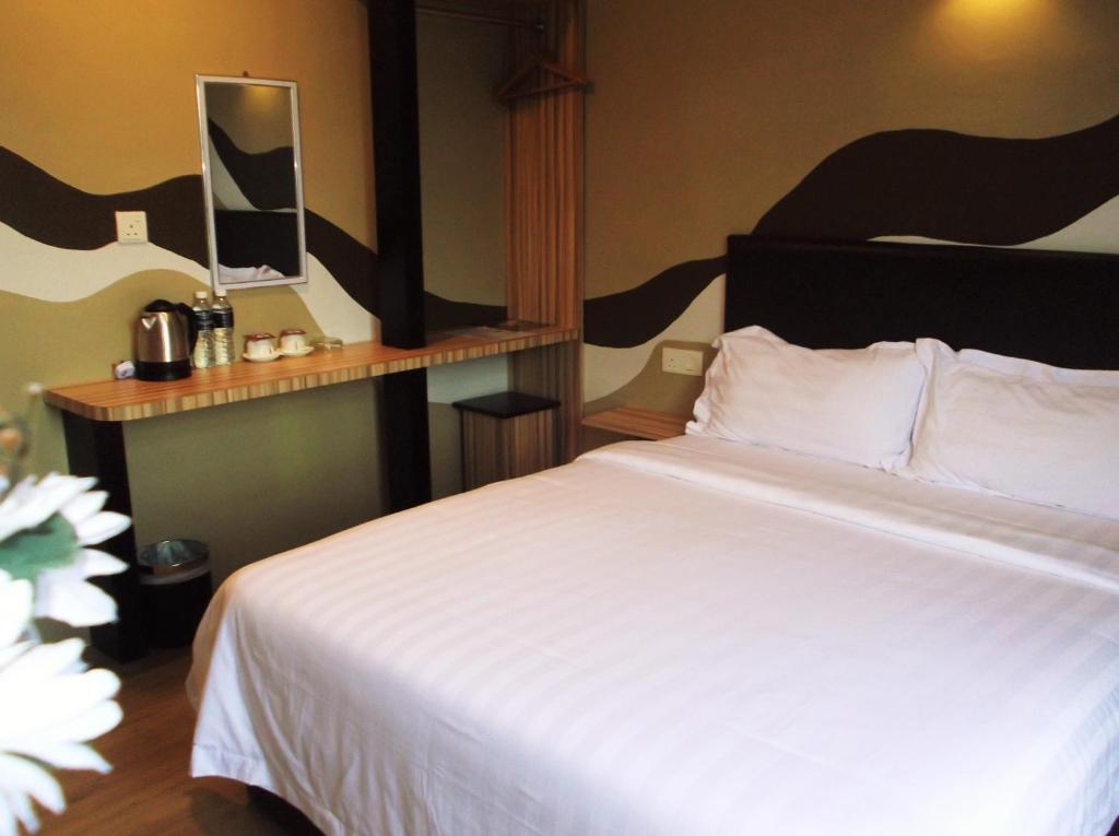 a bedroom with a large bed with a white bedspread at HOTEL SRIMPIAN ROMPIN in Kuala Rompin