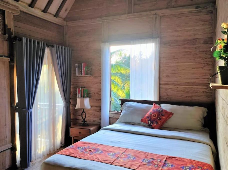 a bedroom with a bed and a large window at Jungle Haven Bali - Eco Lodge in Meliling