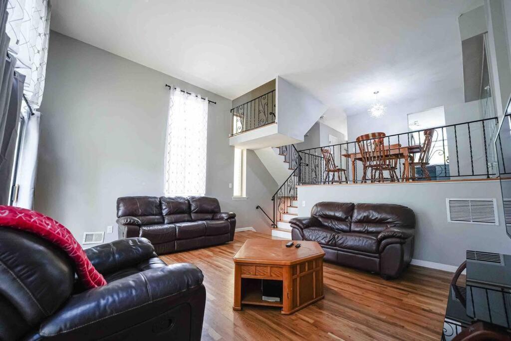 a living room with leather furniture and a staircase at Castle in Queens Fit for Royalty in Rosedale