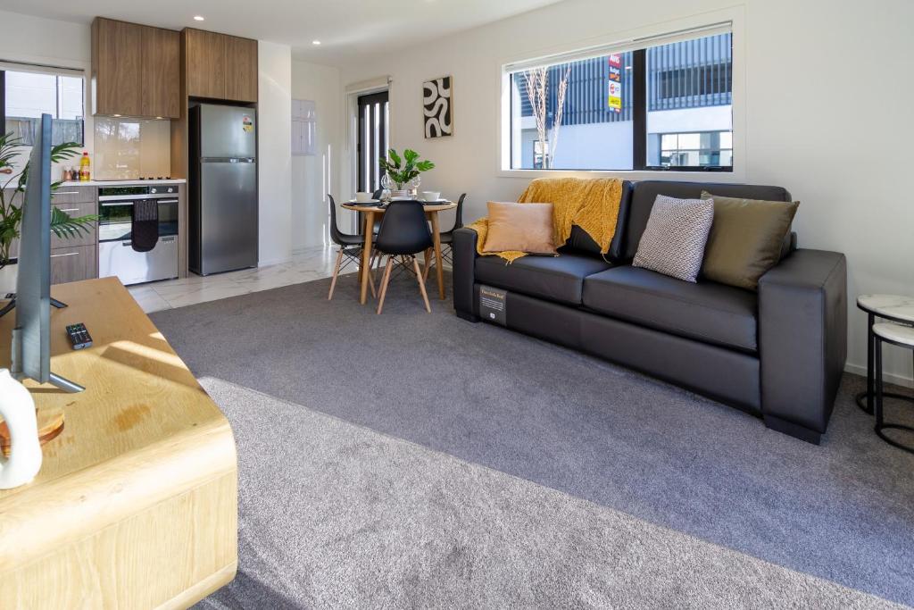 a living room with a black couch and a kitchen at Avon Haven City Escape - 1 bed 1 bath in Christchurch