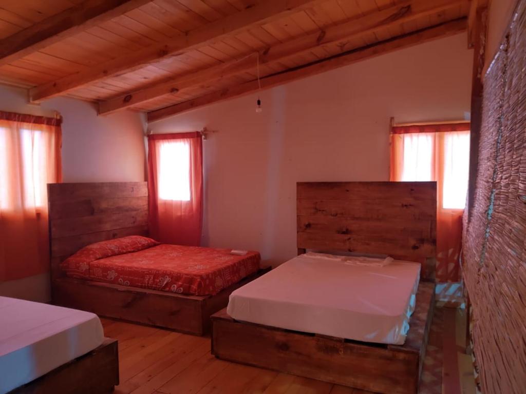 two beds in a room with wooden floors and windows at Preciosa cabaña rústica 