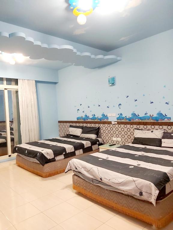 two beds in a room with blue walls at Happy Heart B&amp;B in Taitung City